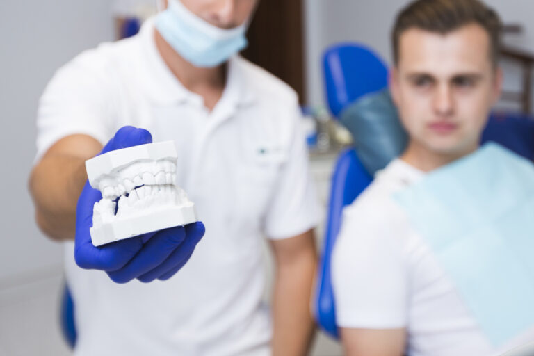 defocused-dentist-holding-dentures-with-patient